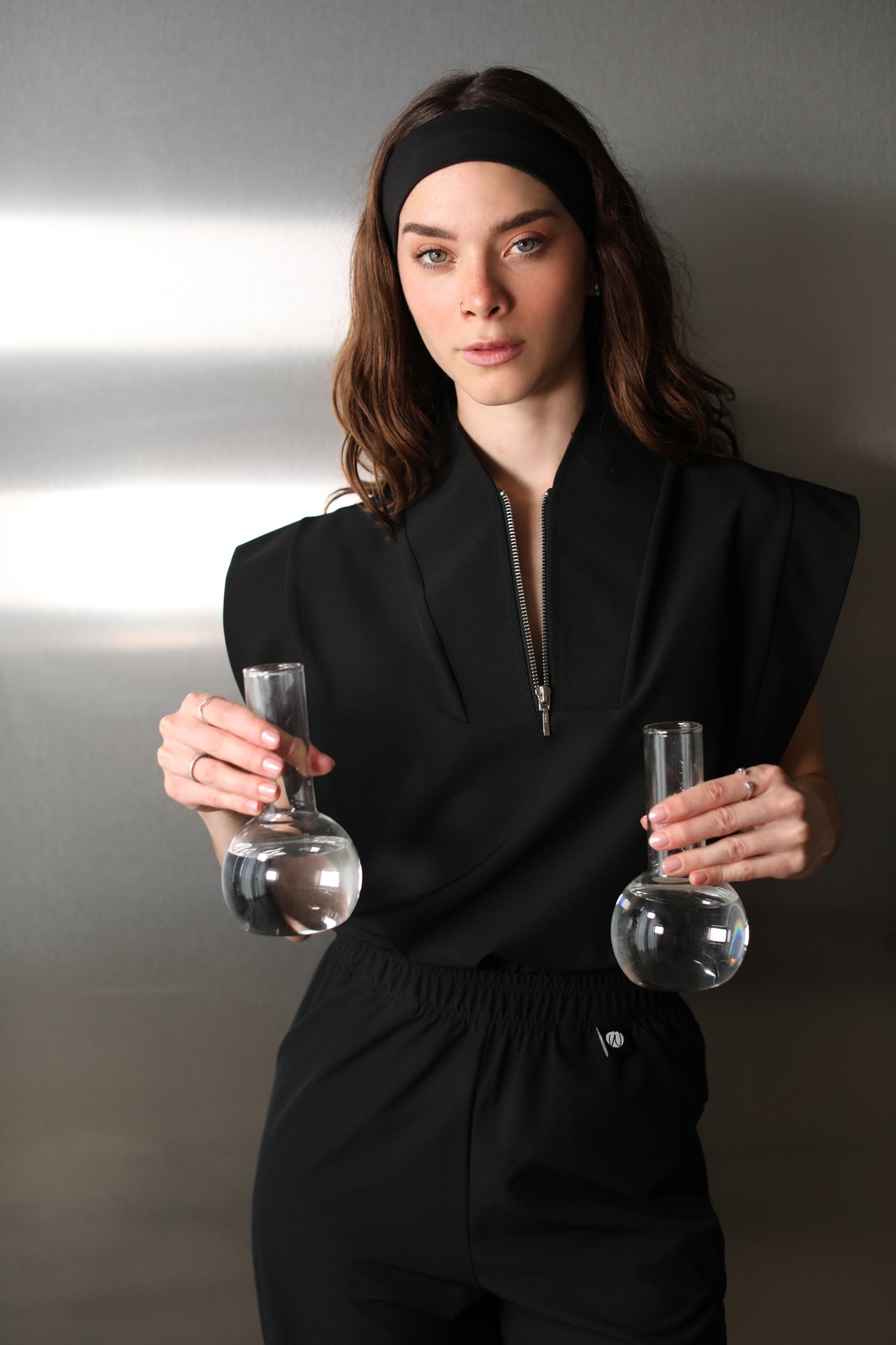 Woman wearing the Kate Black W&C Shield™ scrub top while holding two laboratory flasks filled with clear liquid.